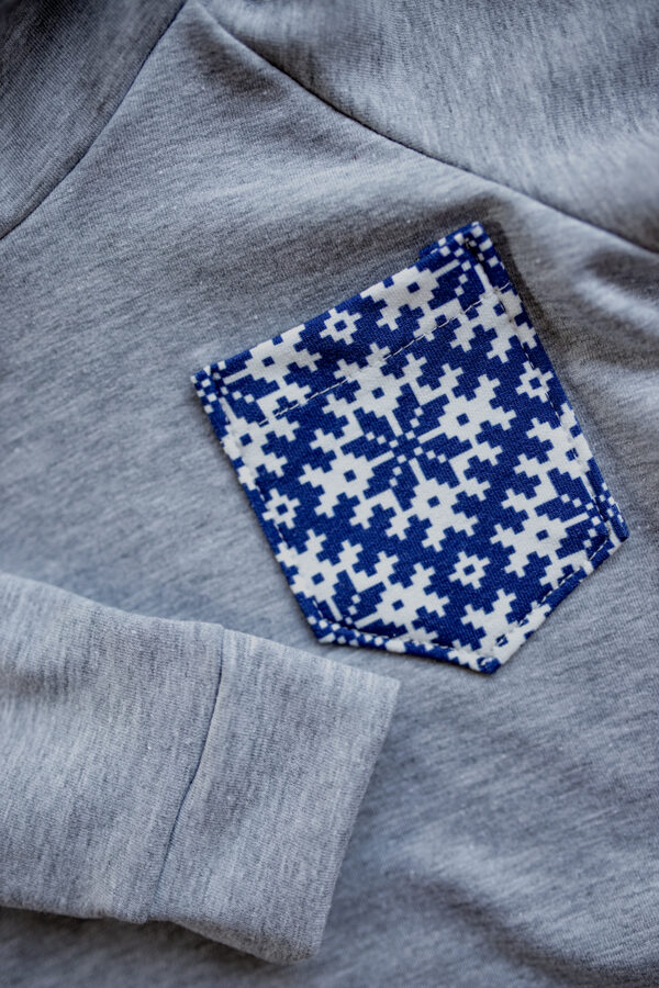 Džemperis gaiši pelēkā krāsā ar mazu zilo latvisko kabatu