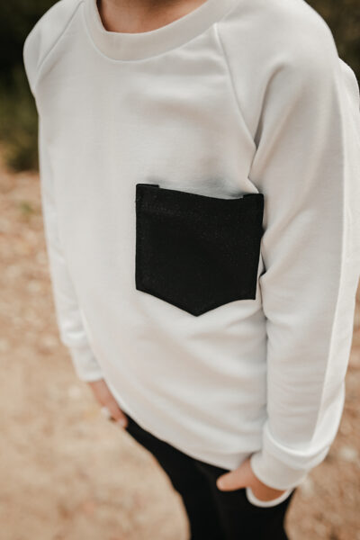 Balts džemperis ar melnu kabatiņu